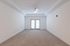 Spacious living room with plush carpeting, modern ceiling fan, and natural light from French doors, perfect for relaxation.