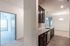 Modern apartment interior featuring sleek kitchen with dark cabinetry, bright living area, and inviting carpeted bedroom.