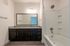 Contemporary bathroom featuring a sleek countertop, elegant mirror, and a modern shower-tub combo.