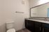 Modern bathroom showcasing sleek dark cabinetry, spacious granite countertop, and a wide mirror for a luxurious feel.