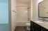 Modern bathroom featuring sleek fixtures, a granite countertop, and a spacious bathtub with elegant wood flooring.