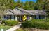 Charming single-story leasing office with a welcoming front porch, surrounded by lush greenery and decorated with festive gold balloons.