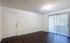 Bright and inviting living space featuring sleek hardwood floors, a large window with vertical blinds, and a contemporary light fixture.