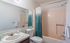 Inviting bathroom featuring a sleek vanity, modern fixtures, and calming teal shower curtain.