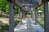 Inviting lakeside boardwalk enveloped by lush green forest, leading to a charming wooden gazebo over tranquil waters.