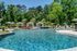 Luxurious outdoor swimming pool surrounded by lush greenery and stylish cabanas, perfect for relaxation.