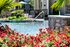 Inviting outdoor pool with cascading water feature surrounded by colorful garden and lush greenery.