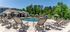 Luxurious outdoor pool area with elegant lounge chairs and shaded cabanas, surrounded by lush greenery and modern architecture.