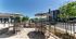 Charming outdoor patio area with stylish furniture, umbrellas, and a built-in grill, perfect for entertaining in a sunny community setting.