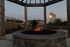 Inviting outdoor fire pit area with a pergola, surrounded by lush landscaping and modern apartment buildings, perfect for evening relaxation.
