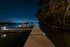 Serene waterfront dock illuminated by soft lights under a clear night sky, perfect for tranquil evening strolls.