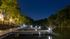 Serene night view of a well-lit dock alongside a lush, green forest under a starlit sky, offering a peaceful lakeside experience.
