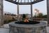 Charming outdoor area featuring a cozy stone fire pit with beautiful landscaping and modern apartments in the backdrop.