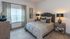 Cozy and stylish bedroom with modern decor, featuring plush carpet, elegant lamps, and patterned furnishings.