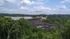 Scenic view of a picturesque dam surrounded by lush greenery and a serene lake under a partly cloudy sky.