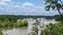 Scenic river view with lush greenery and a picturesque bridge under a vibrant blue sky.