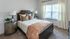 Inviting bedroom with elegant wooden bed, plush pillows, and abundant natural light through large window.