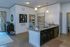 Modern apartment kitchen with elegant granite countertops and ambient lighting, offering a view into a cozy, stylishly decorated bedroom.