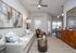 Contemporary living room with cozy gray sofa, abstract art, and open-plan kitchen featuring stylish bar stools and elegant lighting.