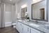 Elegant bathroom with dual sinks, granite countertops, and modern lighting, featuring a large mirror and stylish decor.