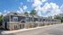 Charming row of modern townhouses with stone accents, nestled in a serene neighborhood under a bright blue sky.