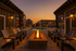Exquisite outdoor area with a cozy fire pit surrounded by elegant seating and a sparkling pool, framed by modern apartment buildings at sunset.