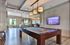 Luxurious game room featuring a sleek billiards table, modern lighting, and a flat-screen TV, ideal for entertainment and relaxation.
