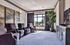 Inviting living room with plush armchairs, large window offering natural light, elegant artwork, and a vibrant indoor plant.