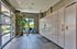 Modern apartment entryway featuring secure parcel lockers, a bicycle, and lush greenery by a sunlit window.
