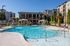 Luxurious apartment complex with a sparkling swimming pool, stylish cabanas, and vibrant landscaping, offering a resort-style experience.