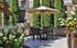 Inviting outdoor patio with a stylish dining set, vibrant flowers, and a state-of-the-art grill, perfect for entertaining and relaxing in a lush garden setting.