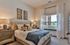 Inviting bedroom with a plush bed, cozy pillows, elegant decor, and a sunlit window with white curtains.
