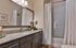 Elegant bathroom with modern vanity, granite countertop, large mirror, and a bright shower area with a crisp white curtain.