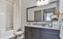 Contemporary bathroom with elegant granite countertop, large mirror, modern lighting, and decorative elements for a cozy atmosphere.