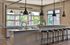 Sleek modern kitchen with stylish industrial pendant lights, granite countertops, and chic bar seating, offering a bright and inviting space.