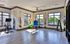 Bright, spacious fitness room featuring an exercise bike, resistance bands, and colorful stability balls with large windows for natural light.