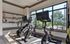 Modern fitness room with bright windows, featuring high-tech exercise bikes, sleek shelving, and vibrant outdoor views.