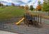 Charming outdoor playground with vibrant yellow slide, set against a backdrop of lush green hills and colorful autumn trees.