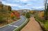 Charming apartment complex nestled in vibrant autumn foliage with a scenic driveway leading to serene living spaces.