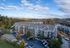 Scenic aerial view of a charming apartment complex nestled in lush, colorful autumn foliage, with ample parking and a tranquil suburban setting.