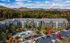 Breathtaking aerial view of a luxurious apartment complex surrounded by vibrant autumn foliage and rolling hills, featuring a central swimming pool and ample parking.