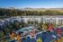 Aerial view of an elegant apartment complex nestled beside scenic mountains, featuring a sparkling pool, spacious balconies, and vibrant autumn trees.