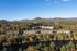 Scenic aerial view of modern apartment complex nestled amidst vibrant autumn foliage and mountainous backdrop along a tranquil river.
