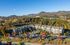 Aerial view of luxurious apartment complex nestled in vibrant autumn foliage with scenic mountain backdrop, highlighting ample parking and beautiful landscaping.