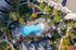 Vibrant aerial view of a luxurious apartment complex featuring a resort-style swimming pool surrounded by lush greenery, cozy seating areas, and elegant walkways.