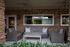 Charming patio space with elegant wicker furniture and rustic stone facade, perfect for relaxing with friends.