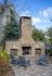 Charming outdoor space featuring a stone fireplace with cozy Adirondack chairs and lush greenery for a relaxing vibe.