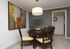 Elegant dining room featuring a round dark wood table with cushioned chairs, modern abstract art, and a stylish pendant light.