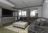 Modern living room featuring a plush sectional sofa, elegant ottoman, wall-mounted TV, and large windows for natural light.