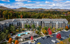 Charming apartment complex nestled in vibrant autumn scenery, featuring a refreshing pool and lush landscaping with mountain views in the background.